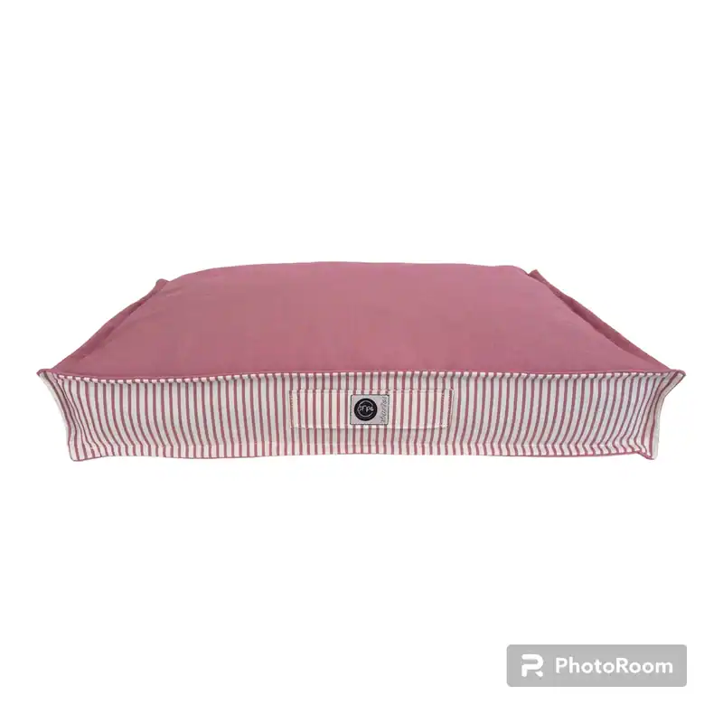 Alfombra para mascotas color rosa con borde a rayas blancas y rojas.