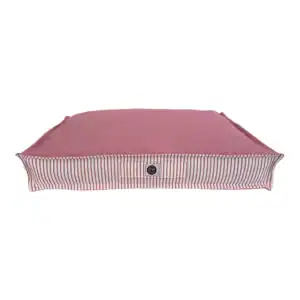 Alto text: Cama para mascotas rosa con borde rayado y funda suave.
