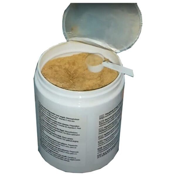 Polvo de suplemento vitamínico para mascotas en envase blanco con tapa abierta y cucharilla.