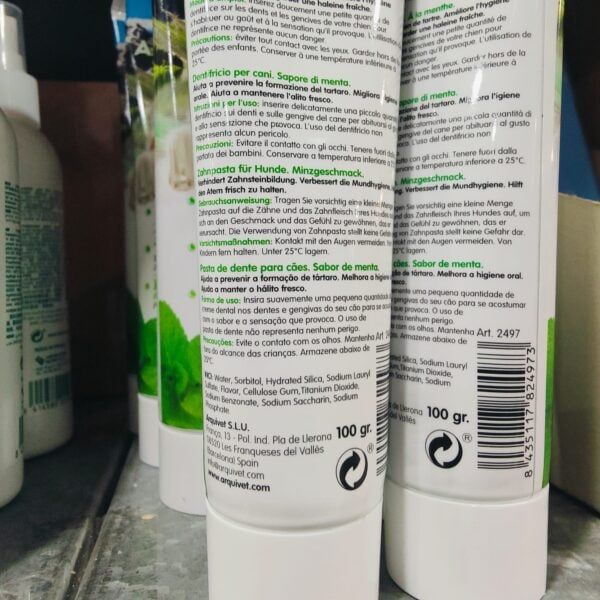 Tubo de pasta de dientes para perros en envase blanco con información en varios idiomas.