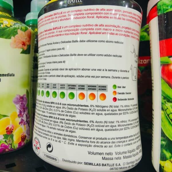Bote de fertilizante líquido con etiqueta en español, plantas y flores en el fondo.