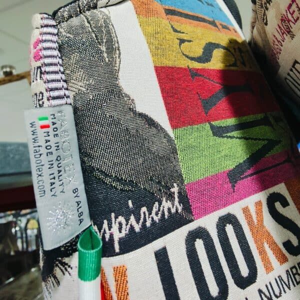 Colorido cojín de taza con diseño vintage y letras en tonos vibrantes para decoración.