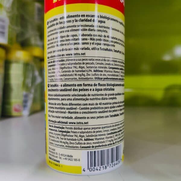TetraMin alimento en escamas para peces con nutrientes esenciales y agua cristalina, promueve crecimiento saludable.
